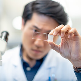 male-physician-reviewing-a-glass-slide-in-a-lab