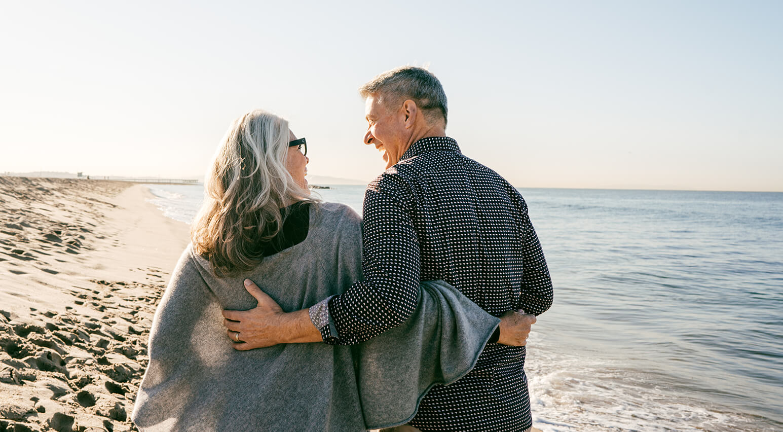 older couple walking on the beach laughing