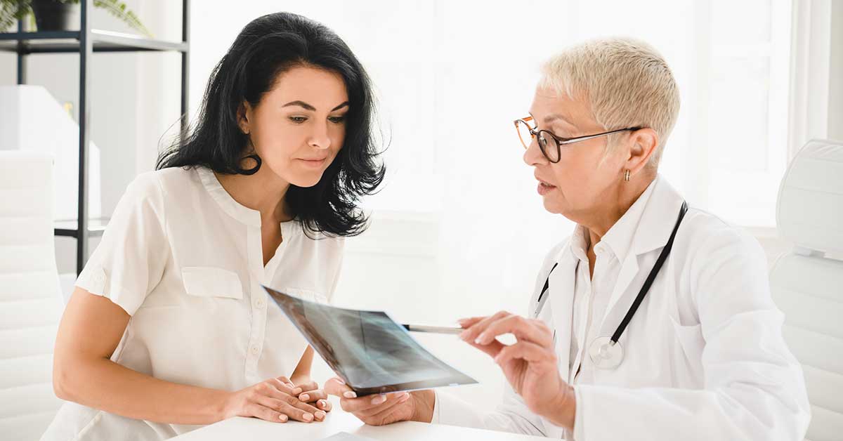 female doctor general practitioner showing x-ray lungs photo to female patient