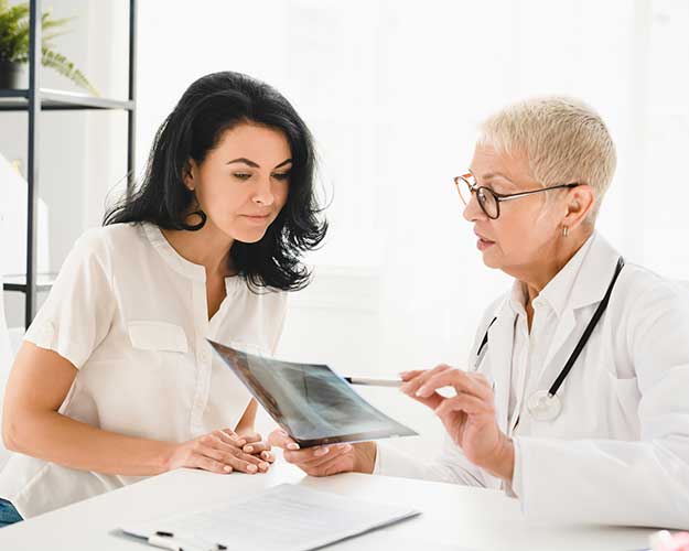 female doctor general practitioner showing x-ray lungs photo to female patient