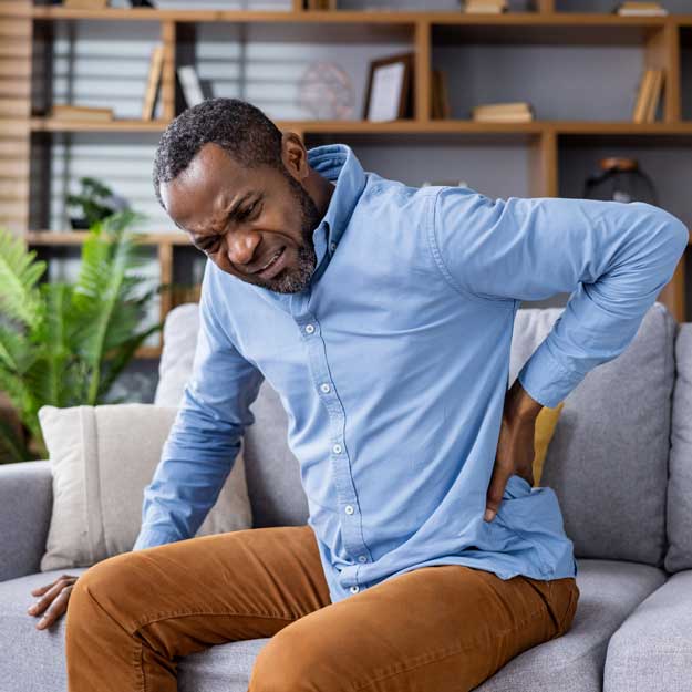 Man with back pain sitting on couch