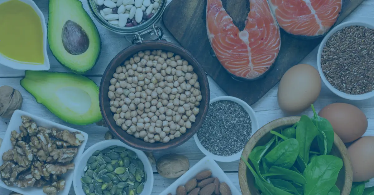 A spread of nutrient-rich whole foods including salmon, avocado, eggs, chickpeas, walnuts, spinach, and seeds — examples of minimally processed NOVA Group 1 foods that support cancer health.