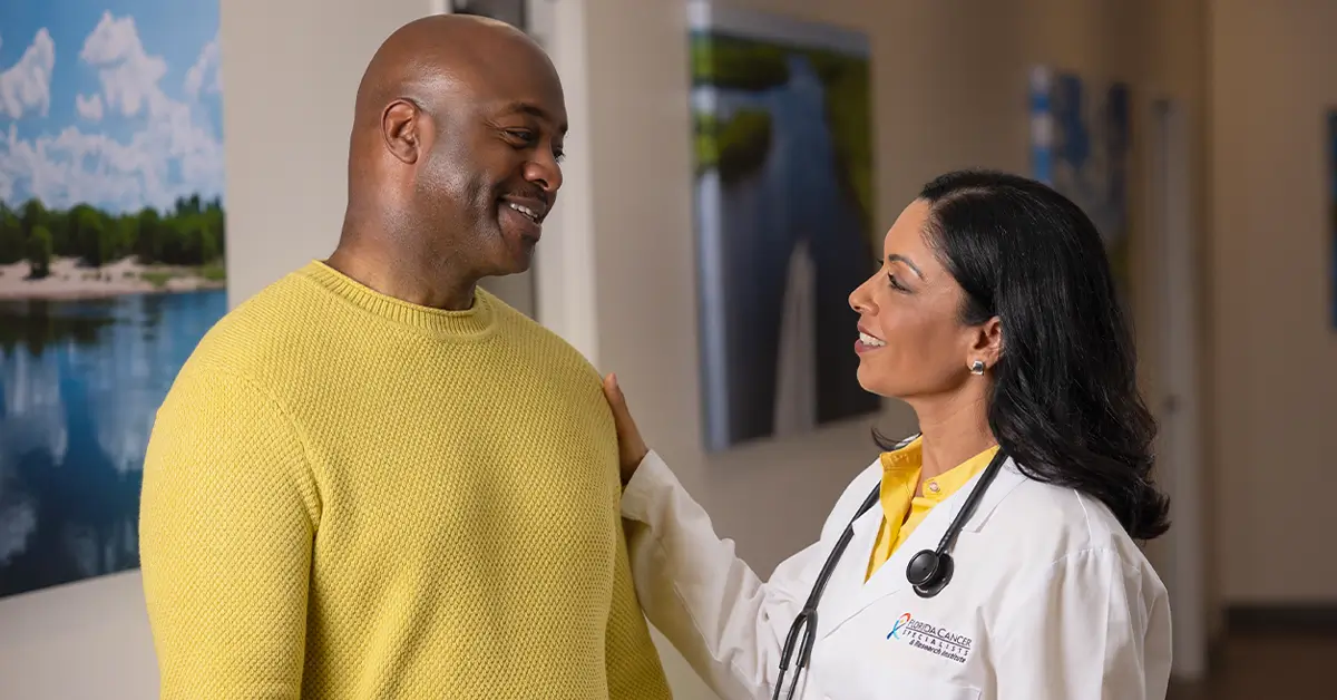 A patient speaking with his cancer care provider in a clinic hallway