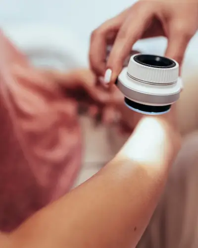 Skin cancer screening exam with a dermatoscope Clinician using a dermatoscope to examine a patient's arm during a skin cancer screening